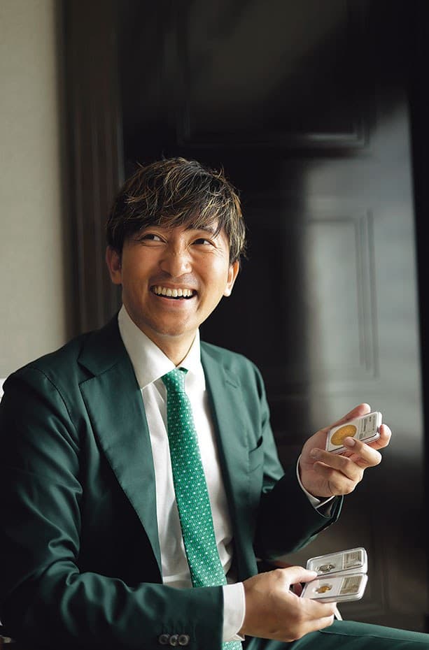 鑑定ケース入りのコインを手にする葉山満
